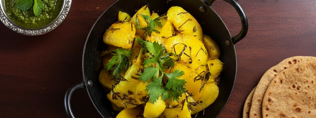 Crispy and spicy Aloo ke Gutke — a popular Kumaoni potato dish tempered with mustard seeds and red chilies, served with curd and bhang ki chutney.